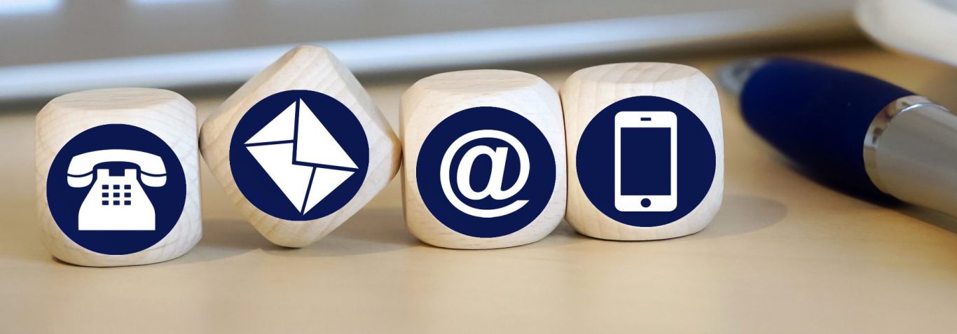 Drei Holzblöcke mit Symbolen für E-Mail, @-Zeichen und Smartphone.